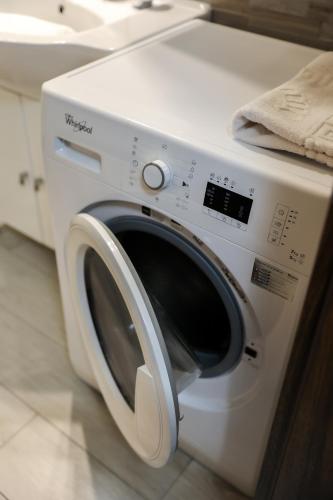 a white washing machine sitting in a kitchen at Casa Luxury Wellness Apartman By BLTN in Siófok