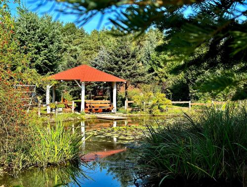 un cenador en un jardín con un estanque en Domki Letniskowe Między Jeziorami w Lipnicy, en Lipnica