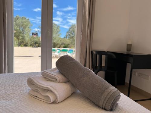 una pila de toallas sentadas en una cama con ventana en Son Virgili Es Trenc, en Campos