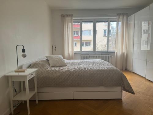 a white bedroom with a bed and a window at Nyrenoverat i centrala Stockholm in Stockholm