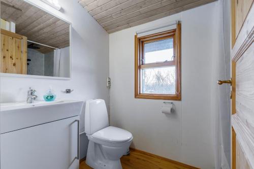 a bathroom with a toilet and a sink and a window at Cabin Úthlíð - Birta Rentals in Úthlid