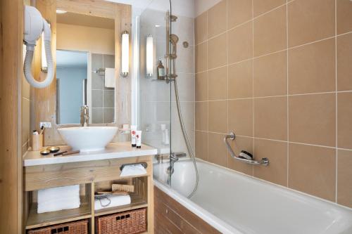 une salle de bain avec une baignoire et un lavabo dans l'établissement Résidence Pierre & Vacances Premium Les Terrasses d'Eos, à Flaine
