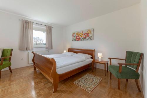 a bedroom with a bed and two chairs and a window at Cozy Garden Flat in Ljubljana