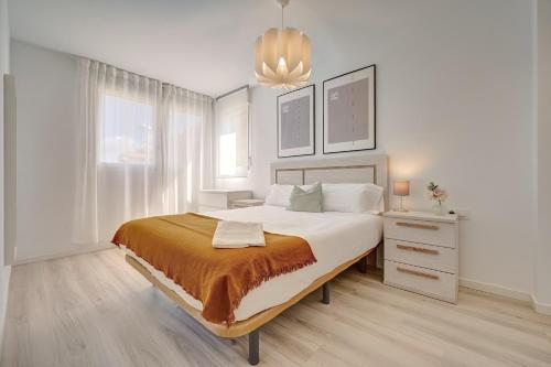 Habitación blanca con cama grande y lámpara de araña. en Zizur Confort by CLABAO, en Zizur Mayor