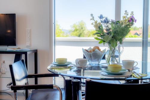 a glass table with a vase of flowers and coffee cups at Penthouse Moos in Moos
