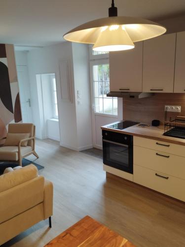 Il comprend une cuisine équipée d'une cuisinière. - un four supérieur à côté d'un salon dans l'établissement La petite Madeleine, à La Rochelle