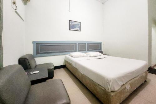 1 dormitorio con 1 cama y 1 silla en RedDoorz Syariah Near Pelabuhan Sri Bintan Pura Tanjungpinang, en Tanjung Pinang