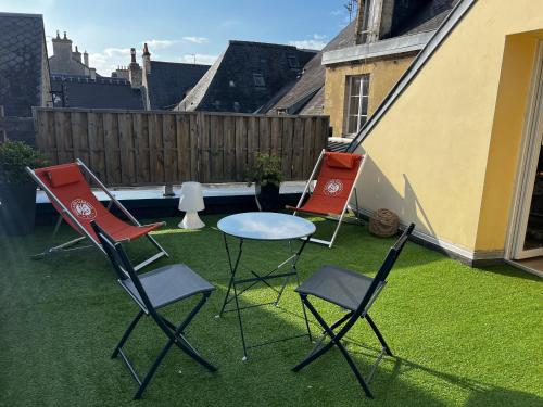 3 sillas y una mesa en el césped en Le Clos Saint Patrice, en Bayeux