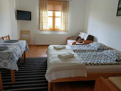 1 dormitorio con 2 camas, mesa y ventana en Noclegi "Koniadów", en Solina