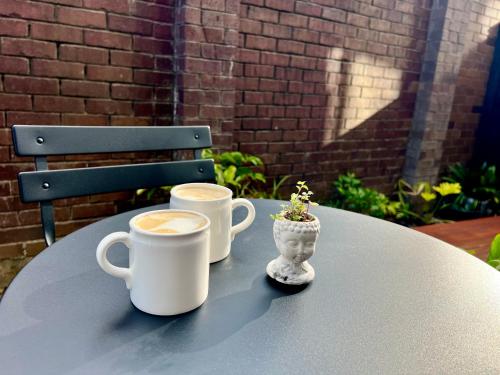 dos tazas de café sentadas en una mesa en Wheturangi Urban Escape, en Auckland