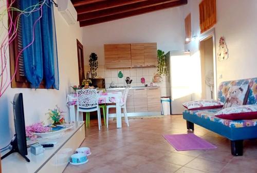 sala de estar con sofá, mesa y cocina en Conchiglietta blu, en Cardedu