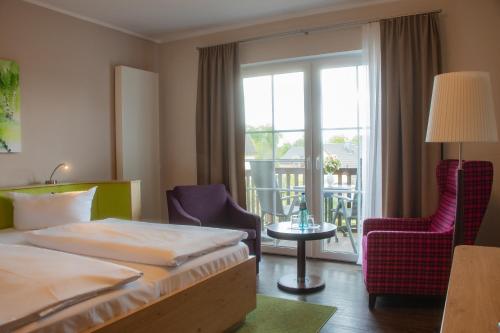 ein Hotelzimmer mit einem Bett und Stühlen sowie einem Balkon in der Unterkunft Hotel Bleske im Spreewald in Burg