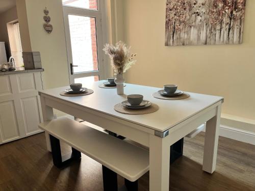 a white table with cups and saucers on it at 4 bedroom, sleeps 8, 30 seconds from beach, games table in The Mumbles