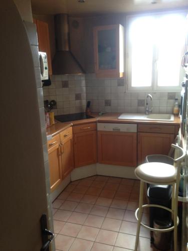 une cuisine avec des armoires en bois, un évier et une fenêtre dans l'établissement Guest house dans appartement sur Paris, à Paris