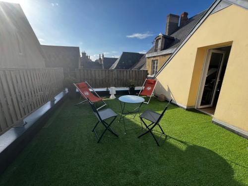 d'une terrasse avec 3 chaises et une table sur gazon. dans l'établissement Le Clos Saint Patrice, à Bayeux
