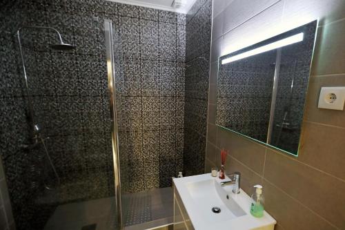 a bathroom with a sink and a shower with a glass door at Casa da Calheta in Maia