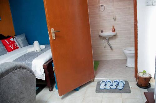 a bedroom with a bed and a bathroom with a sink at Little Lillies Homestays Nakuru in Nakuru