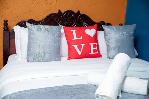 a bed with red and blue pillows with the words love at Little Lillies Homestays Nakuru in Nakuru