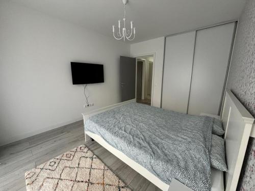 a bedroom with a bed and a tv on a wall at White DeLuxe Apartment in Ploieşti