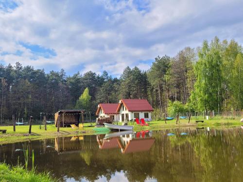 a small house on the shore of a lake at Kemping i Domki nad stawem in Harsz
