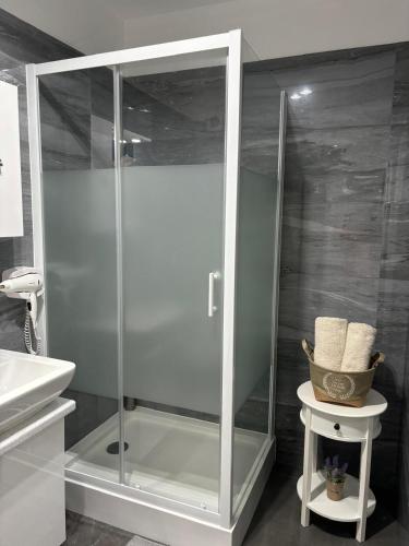 a glass shower in a bathroom with a sink at White DeLuxe Apartment in Ploieşti