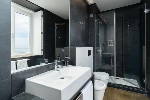 a bathroom with a white sink and a toilet at Limehome Lisbon Calçada do Cardeal in Lisbon
