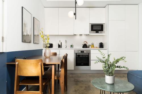 a kitchen with white cabinets and a table and chairs at Limehome Lisbon Calçada do Cardeal in Lisbon