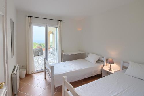 a white room with two beds and a window at Casa Chula in Begur