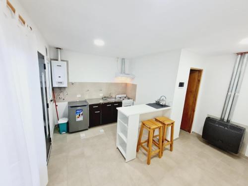 a kitchen with a counter and two stools in it at Departamentos temporarios Rg in Río Grande
