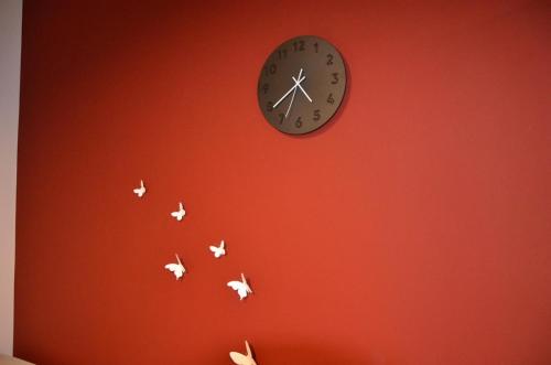 a clock on a red wall with butterflies at Interno 23 Duomo Apartment in Udine