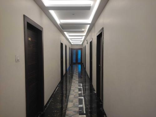 a corridor with white walls and a hallway with black doors at Hotel O MAIREAD in Sopāra
