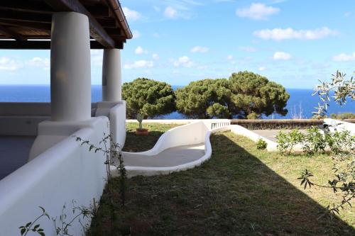 a white bench on the side of a house overlooking the ocean at Case a Malfa - Alba & Rosina, Isola Salina in Malfa
