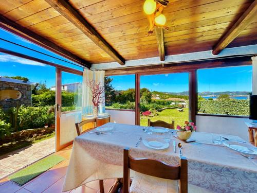 comedor con mesa y algunas ventanas en Vistamare Villetta A Schiera, en Baja Sardinia