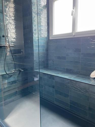 baño con paredes de azulejos azules y ducha. en le luxe à 2 pas de la grande plage en Les Sables-dʼOlonne