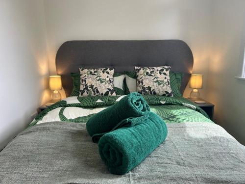 a bed with green towels on it with two lamps at Urban Escape Entire Apartment Near Uni and Hospital in Southampton