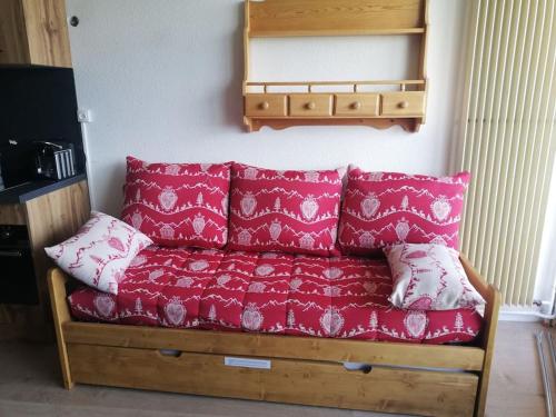 ein rotes Sofa mit roten Kissen in einem Zimmer in der Unterkunft Studio tout confort aux Balcons de Villard de Lans in Villard-de-Lans