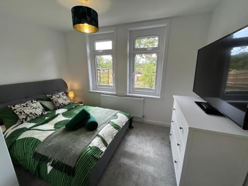 a bedroom with a bed and a desk and two windows at Urban Escape Entire Apartment Near Uni and Hospital in Southampton