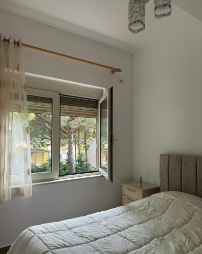 a bedroom with a bed and a window at Apartament Gjiri i Lalëzit in Draç