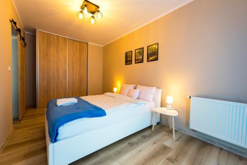 Un dormitorio con una gran cama blanca y una mesa en Ełcka Bryza, en Ełk