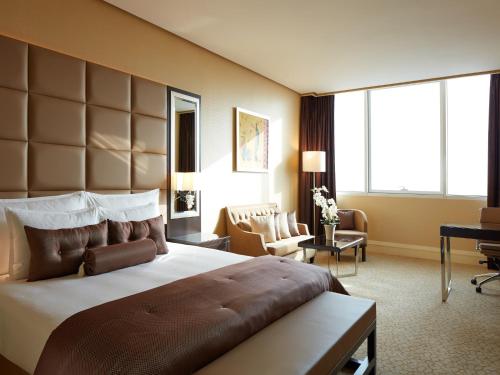 a hotel room with a large bed and a desk at Millennium Hotel & Convention Centre Kuwait in Kuwait