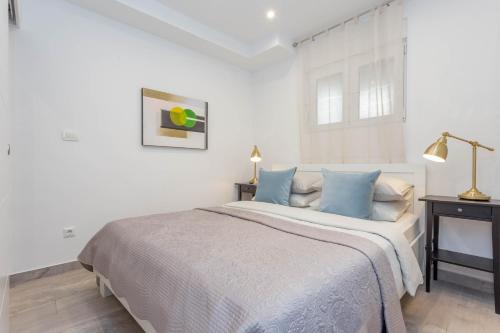 a white bedroom with a large bed with blue pillows at Hvar Pavičić Top View apartments in Hvar