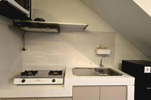 a small kitchen with a stove and a sink at Typo House at Royal Residence in Surabaya