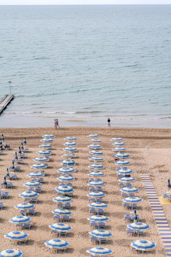 a row of beach chairs in the sand on a beach at Hotel Orizzonte in Lido di Jesolo