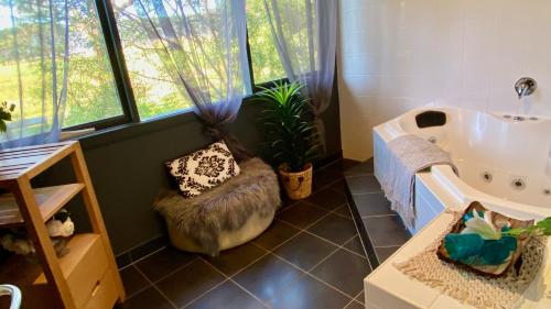 uma casa de banho com uma banheira, uma cadeira e uma planta em Phillip Island Nature Resort Villas em Cowes