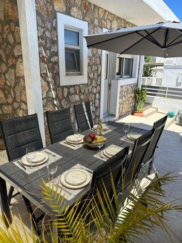 stół z krzesłami i parasol na patio w obiekcie Villa Massari w mieście Charaki