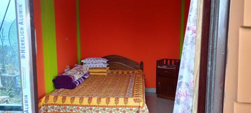 - une chambre avec un lit et un mur coloré dans l'établissement AASHRAYA HOMESTAY, à Paten
