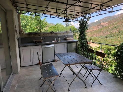 une cuisine avec une table et des chaises sur une terrasse dans l'établissement Maison authentique corse, à Manso