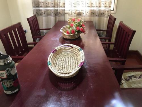 a wooden table with two baskets and flowers on it at Janibichi Adventures hostel in Moshi