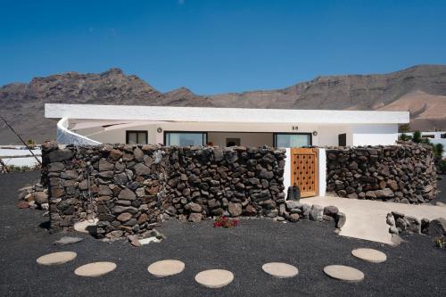 un mur en pierre devant une maison dans l'établissement LANZAROTE FAMARA BEACH BUNGALOW, à Famara