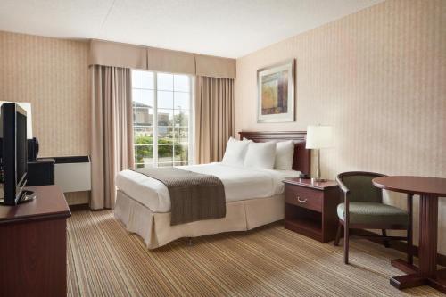 a hotel room with a bed and a desk and a television at Days Inn by Wyndham Brantford in Brantford